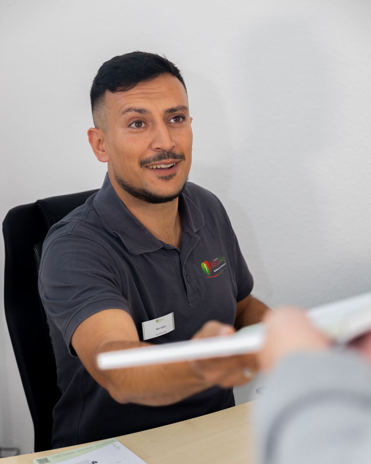 Mitarbeiter im Büro reicht Unterlagen über den Schreibtisch